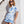Woman wearing a blue and white patterned outfit against a white wall.