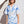 Woman wearing a blue and white patterned dress against a white wall.