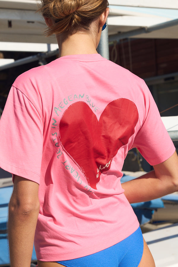 Person wearing a pink t-shirt with a red heart design outdoors