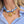 Necklace with sun and heart pendants on a person wearing a blue and white striped shirt.